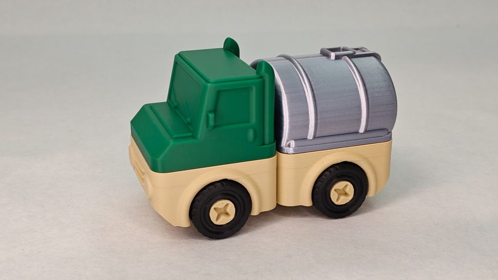 Groene speelgoed vrachtwagen met een zilveren laadruimte en zwarte wielen.